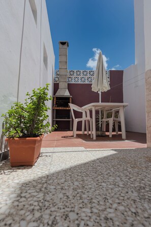 Relax in the serene outdoor patio, complete with a table, chair, and potted plant, perfect for al fresco dining and cooking.