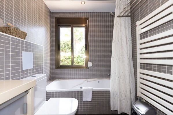 Een badkamer met een bad, toilet en een raam.