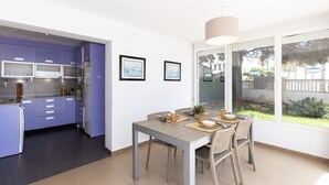 A modern kitchen with purple cabinets, a dining area with a table and chairs, and a large window with a view of the outdoors. - Beachfront apartment perfect for families - UHC GLADIOLS 211 (Cambrils)