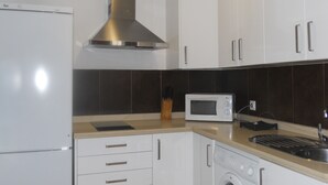 Een keuken met witte kastjes, een roestvrijstalen afzuigkap, een magnetron en een wasmachine.