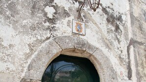 Ein historisches Gebäude mit einem großen Bogenportal, einer grünen Tür mit zwei goldenen Griffen und einem kleinen Schild darüber.