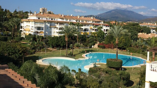 Un complexe hôtelier doté d’une piscine, d’une végétation luxuriante et offrant une vue sur un paysage montagneux.