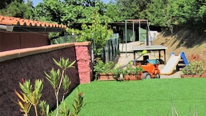 A backyard with artificial grass, a play area, and a small garden with plants. - Villa Giuliana, Two-room apartment 4 Ptl. (Capoliveri)