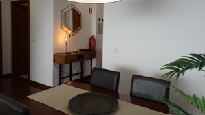 Een eetruimte met een tafel, stoelen, een lamp, een spiegel en een brandblusser.