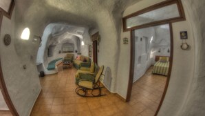 A spacious, curved interior with a cozy seating area, a bed, and a dining table. - BARRETO CAVES. In the center of a 27,000 m. Finca. Mountain and sea views. (Firgas)