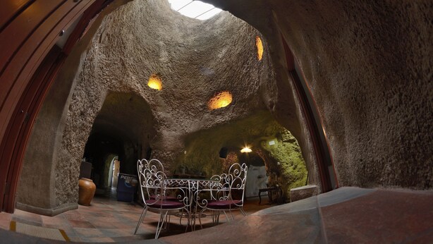 An interior with a stone archway, a table with chairs, and a vase. - BARRETO CAVES. In the center of a 27,000 m. Finca. Mountain and sea views. (Firgas)