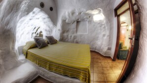 A cozy bedroom with a bed, pillows, and a window. - BARRETO CAVES. In the center of a 27,000 m. Finca. Mountain and sea views. (Firgas)