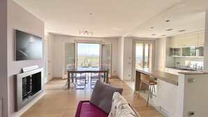 A modern apartment with a dining area, kitchen, and a sofa.