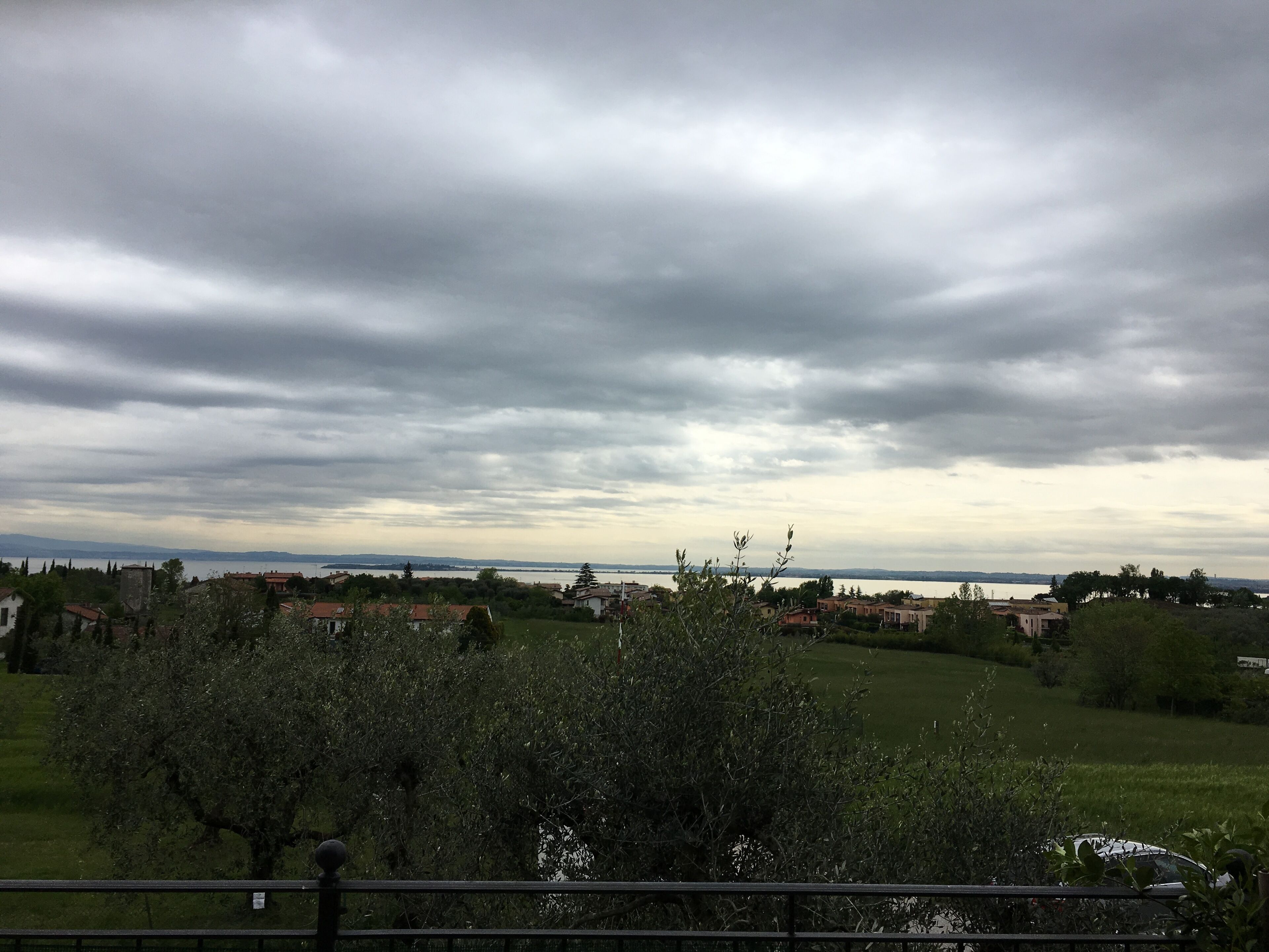A view of a coastal town with houses, a body of water, and a cloudy sky.