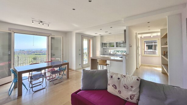 A modern apartment with a dining area, kitchen, and a balcony with a city view.