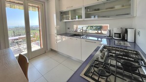 A modern kitchen with a gas stove, white cabinets, and a view of the outdoors.
