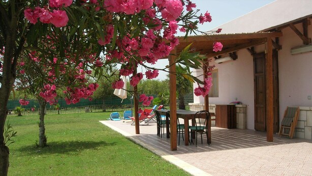 Un patio con mesa y sillas, un espacio de descanso cubierto y una piscina pequeña.