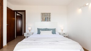 Une chambre à coucher comprenant un lit, une table de chevet, une œuvre d’art accrochée au mur et une porte.