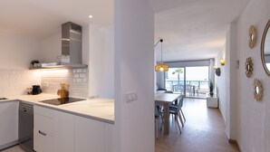 Une cuisine moderne avec des meubles blancs, un lave-vaisselle intégré et une hotte de cuisinière en acier inoxydable.