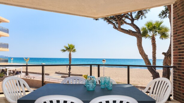 Un balcon avec une table et des chaises donnant sur une plage.