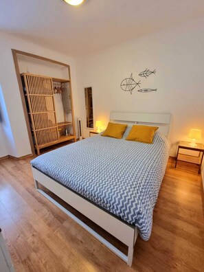 A bedroom with a bed, two bedside tables, a wardrobe, and wall art.
