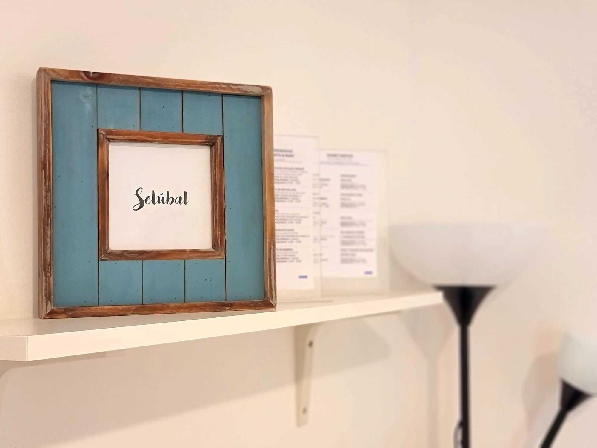 A framed picture with the word 'Stüb' on a white background, placed on a white shelf.