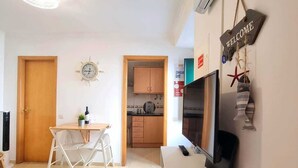 Een knus woongedeelte met een kitchenette, een eethoek, een televisie en een 'WELCOME' bord.