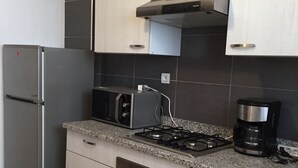 A kitchen with a stainless steel refrigerator, a microwave, a stove, and a coffee maker. - APARTMENT AGADIR GROUND FLOOR <br> (AGADIR)
