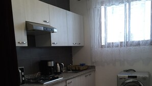 A kitchen with a stove, oven, coffee maker, and a washing machine. - APARTMENT AGADIR GROUND FLOOR <br> (AGADIR)