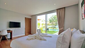 A hotel room with a large bed, a flat-screen TV, a desk, and a view of a swimming pool. - A Luxurious Retreat in Bophut (koh samui)