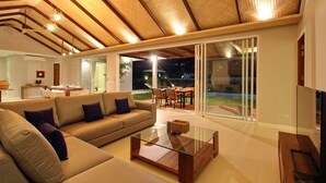 A modern living room with a glass coffee table, a sofa, and a TV. - A Luxurious Retreat in Bophut (koh samui)