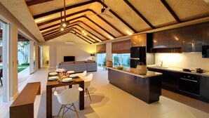 A modern kitchen with a central island, built-in appliances, and a dining area with a bench and chairs. - A Luxurious Retreat in Bophut (koh samui)