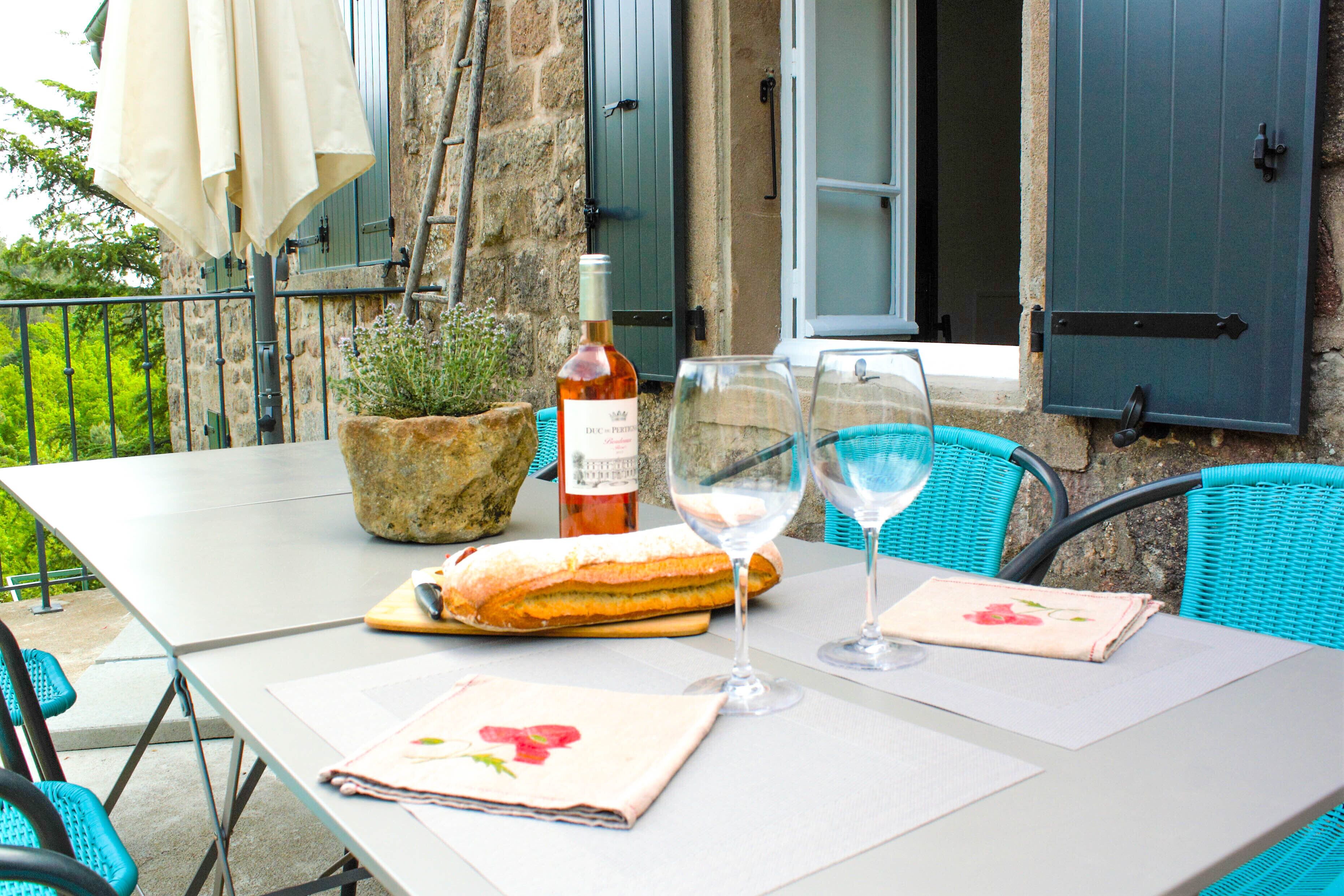 A table set with a bottle of wine, a glass, a sandwich, and a napkin with a floral design.