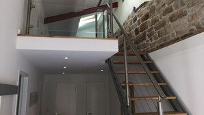 Ein modernes Interieur mit Glasgeländer, Steinwand und Holztreppe.