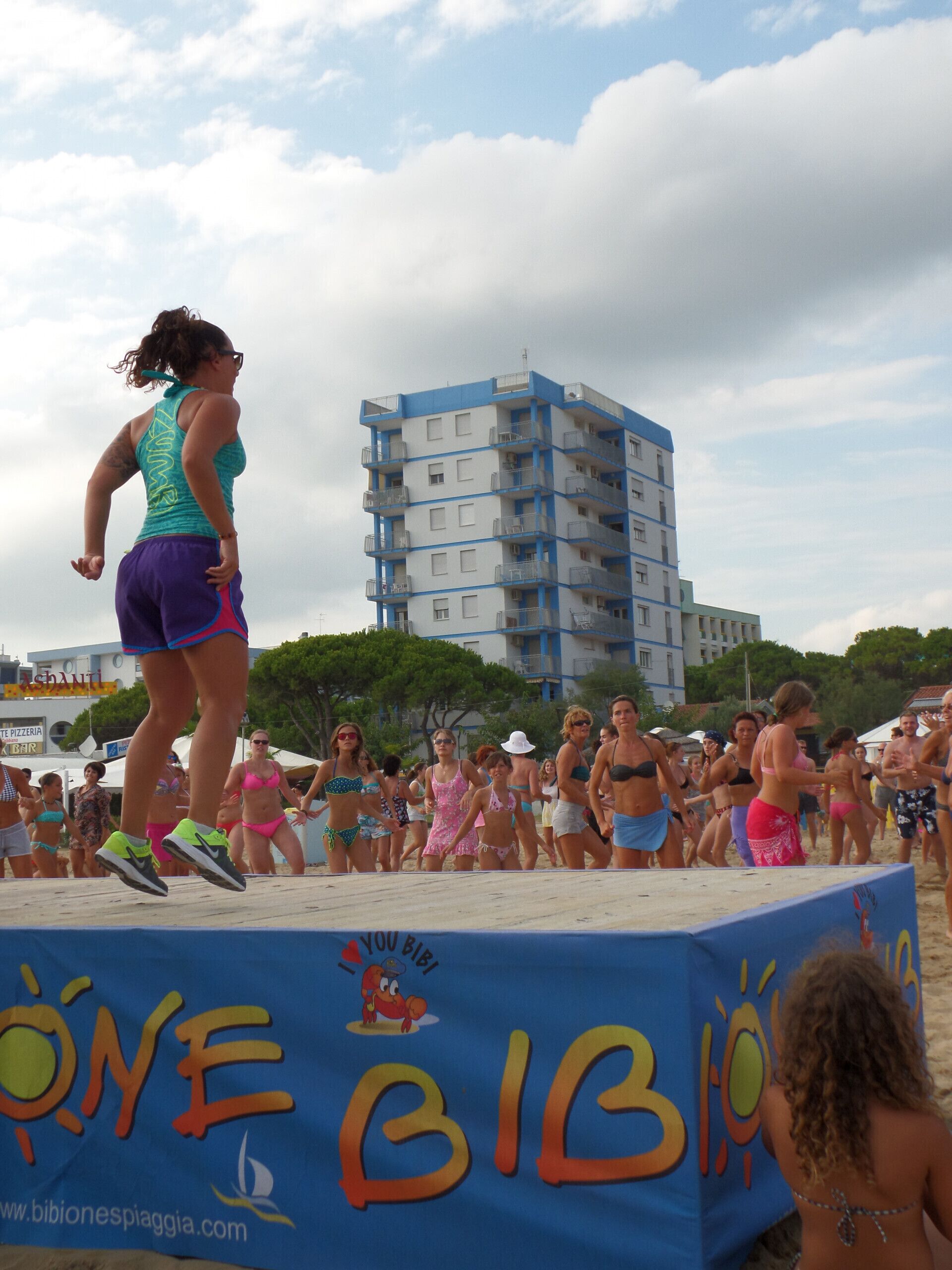 A beach event with a stage and a crowd.