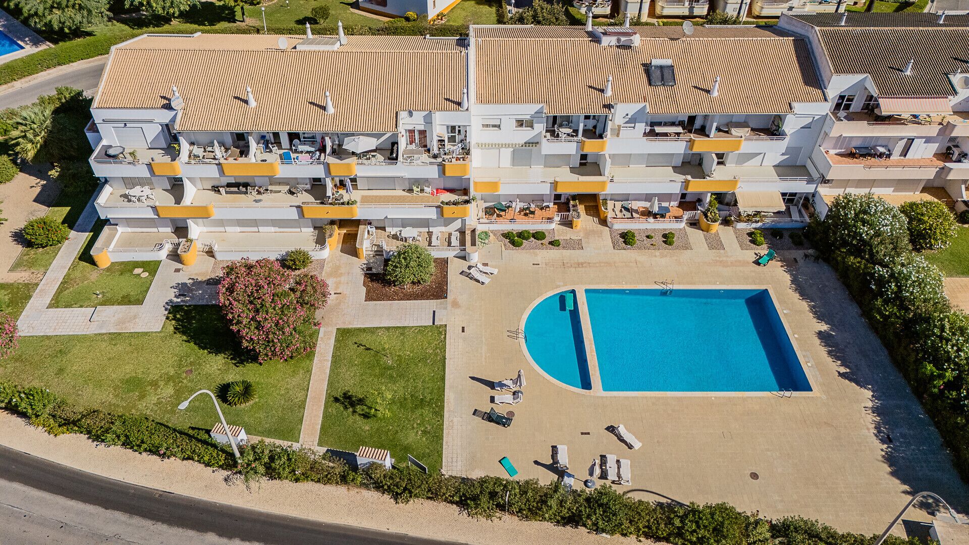 Vista aèria d'un hotel modern de diversos pisos, amb piscina, zones d'estar a l'aire lliure i un jardí paisatjista.