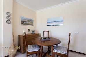 A dining area with a round wooden table, two chairs, a vase, and wall clocks.
