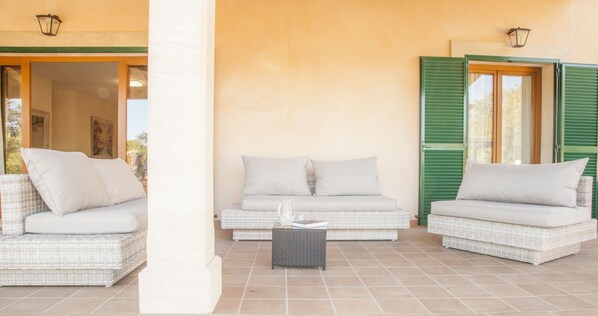 A covered outdoor seating area with wicker furniture and a tiled floor. - Na Clavet. Rural house in a totally natural environment with Wifi and swimming pool (Calonge)