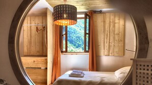 A circular room with a bed, a hanging light fixture, and a window with curtains. - Natural Jacuzzi impressive Gorge in the Picos de Europa (Ponga)