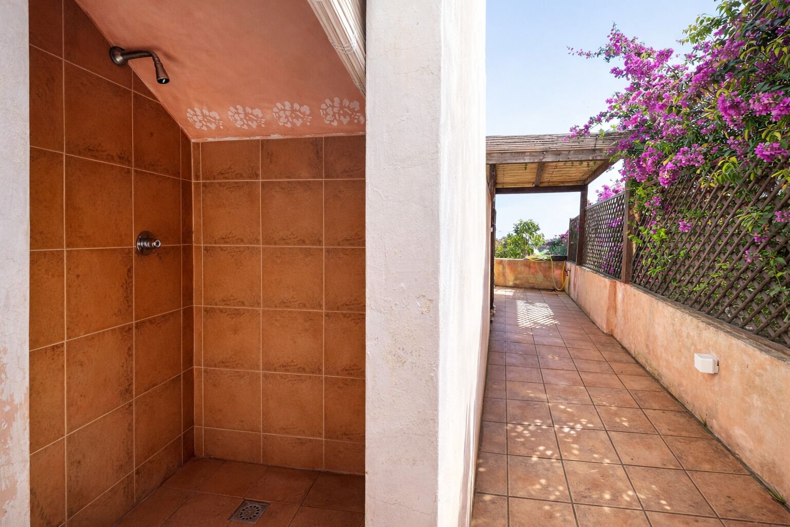 A small, enclosed shower area with a single showerhead and a drain.