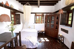 Un dormitorio rústico con cama, muebles de madera, una lámpara colgante y una ventana con luz natural.