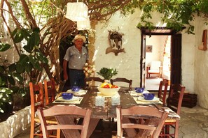 Una mesa de comedor con sillas, un cuenco de fruta y una planta en maceta.