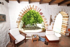 A cozy patio area with a wooden bench, a cushioned seating area, and a small table with cups and a bowl. - Traditional farm house "Langada" (Egeo)