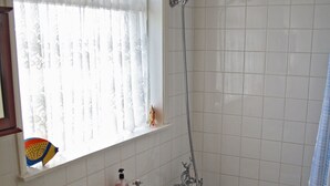 Un baño con bañera, lavamanos y ventana con cortinas.