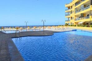 A swimming pool with sun loungers and a building with balconies. - IN FIRST LINE OF THE SEA, WITH AIR CONDITIONED POOL, PRIVATE SOLARIUM and WiFi - 30 (Tenerife)