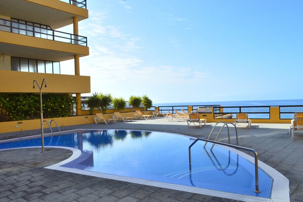 A rooftop pool with clear blue water, surrounded by lounge chairs and a view of the ocean. - IN FIRST LINE OF THE SEA, WITH AIR CONDITIONED POOL, PRIVATE SOLARIUM and WiFi - 30 (Tenerife)