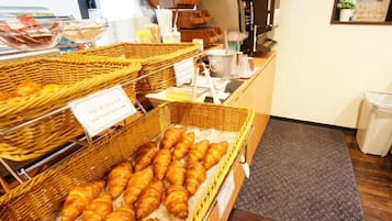 A bakery display with baskets of pastries and a coffee machine.