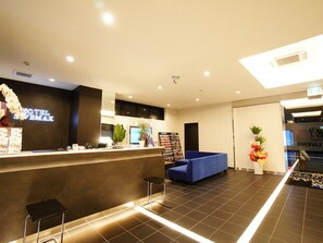 Un hall d’hôtel comprenant un comptoir d’accueil, un espace salon et une grande fenêtre.
