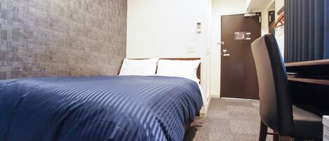 Una habitación de hotel con cama, escritorio y puerta.