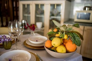 Una mesa de comedor con un cuenco de fruta y copas de vino.