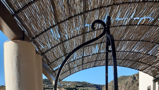 Un'area esterna coperta con pavimento in pietra, una scala a chiocciola in metallo e vista su un paesaggio montuoso.