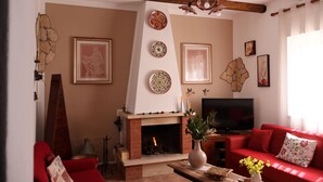 A living room with a fireplace, red sofa, and a television.