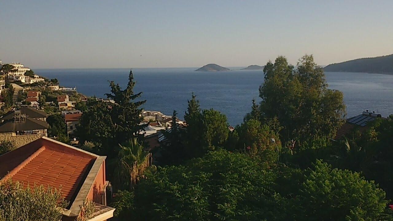 Une ville côtière, avec ses bâtiments et sa végétation, qui offre une vue sur la mer et une île située au loin.