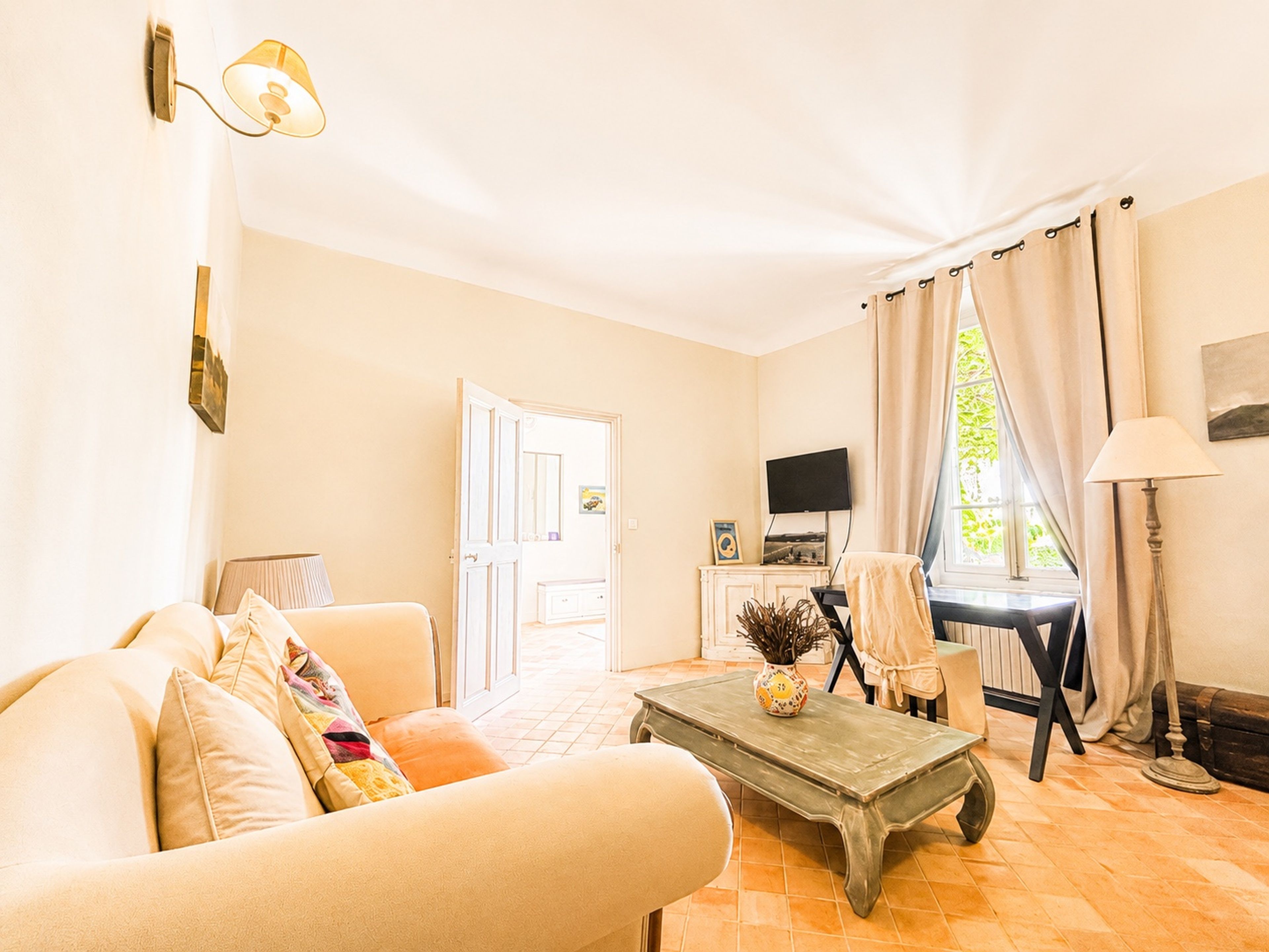 A living room with a sofa, a coffee table, a television, and a door leading to another room.