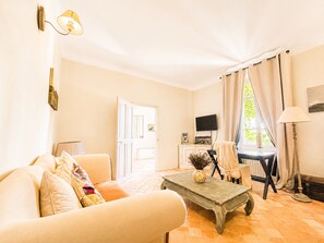 Ein Wohnzimmer mit Sofa, Couchtisch, Fernseher und einer Tür zu einem anderen Raum.